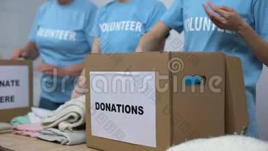 社会中心志愿者把衣服放进捐赠箱里，慷慨无私